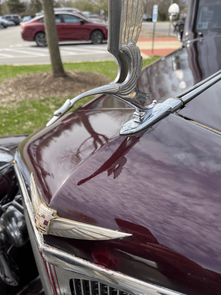 Close-up view of the hood ornament and emblem of a vintage 1933 Cadillac, showcasing its intricate design and polished chrome finish.