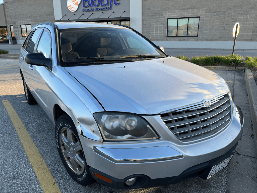 A silver Chrysler Pacifica showing some wear and tear on the front driver's side.