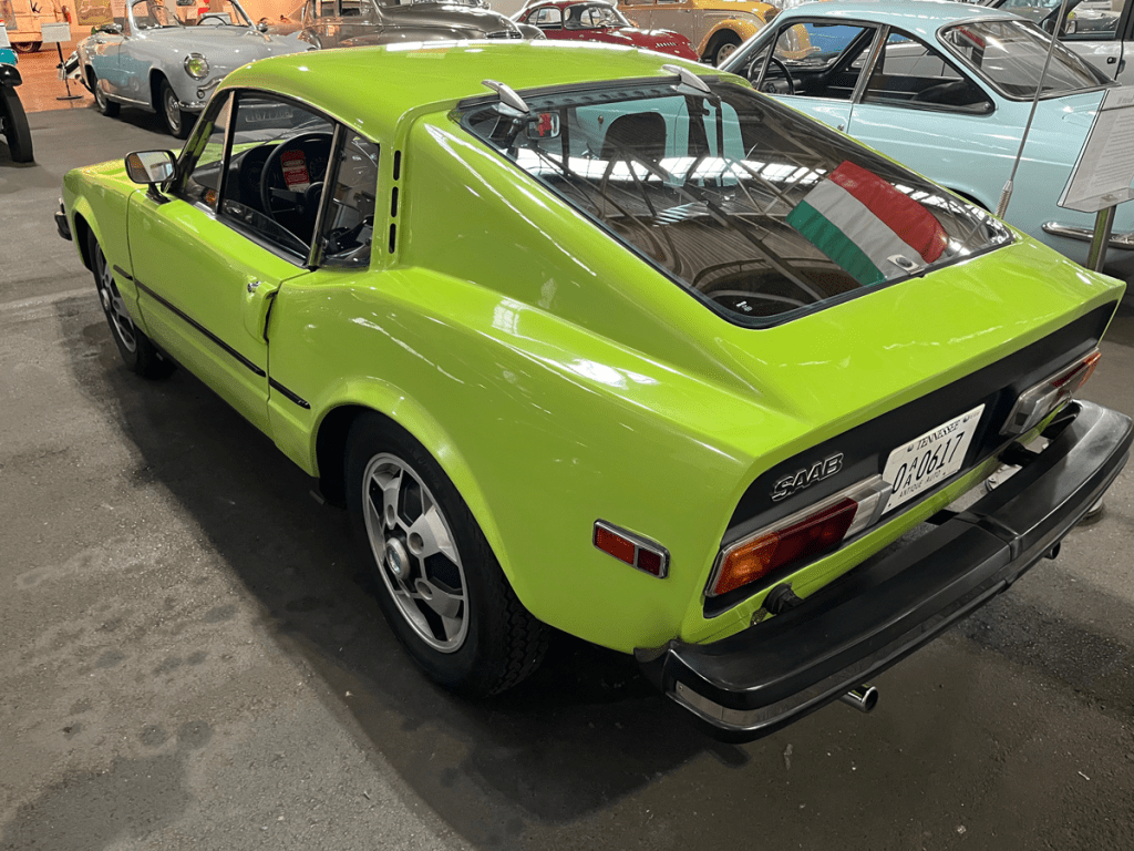A vibrant green Saab Sonett III sports car displayed in a museum, showing its sleek design and distinctive rear profile.