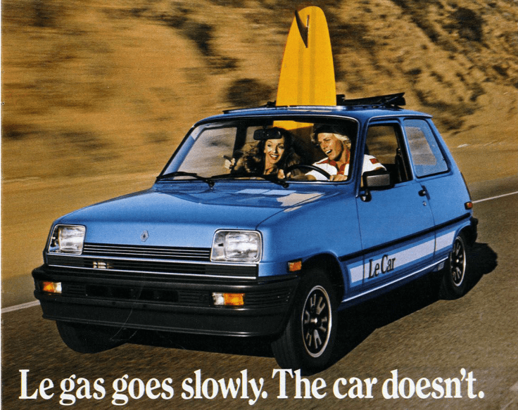 A blue Renault Le Car driving on a sunny road, with a surfboard mounted on the roof and two smiling passengers inside.
