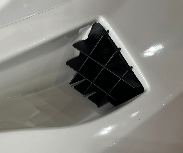 Close-up of a black air intake vent integrated into a white car body, showcasing its angular design on Renault 5 Turbo 2.