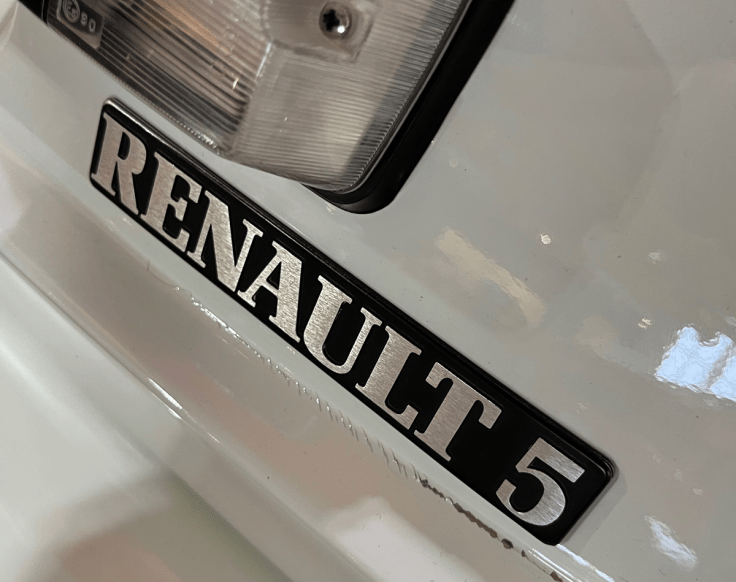 Close-up of a Renault 5 badge on a car, showcasing the distinctive lettering.