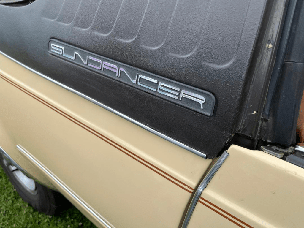 Close-up of the 'Sundancer' badge on the exterior of an AMC car, showcasing the vehicle's unique identity.
