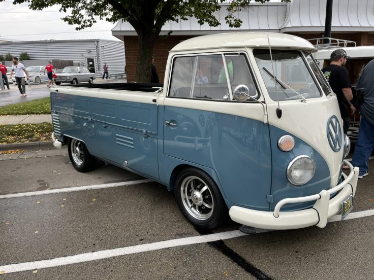 A vintage Volkswagen Single Cab pickup truck in Dove Blue and white parked at a car show, showcasing its unique design and classic features.