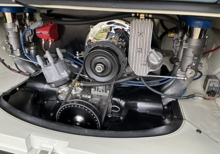 Close-up view of a Volkswagen engine in at Transporter with visible components such as the carburetors, ignition wires, and cooling fan.