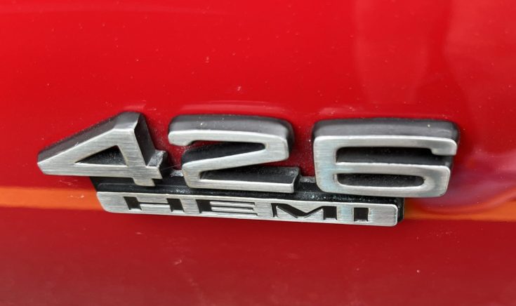 Close-up of the 426 HEMI badge on a red muscle car, emphasizing its powerful engine designation.