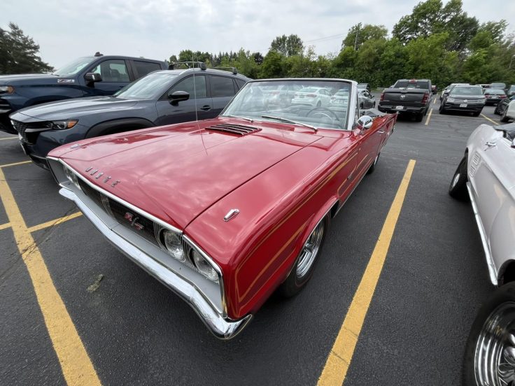 A classic 1967 Dodge Coronet R/T Convertible parked in a lot, featuring a vibrant red color and sleek design.