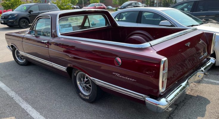 A 1967 Ford Ranchero parked in a lot, showcasing its sleek maroon exterior and truck bed.