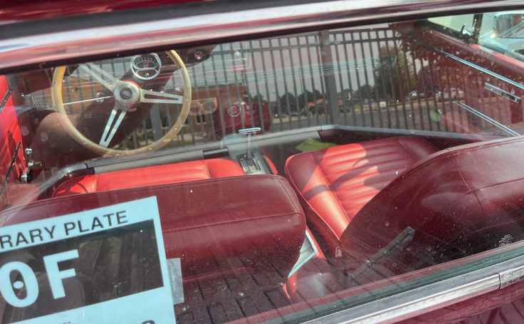 Interior view of a 1967 Ford Ranchero showcasing red leather seats and a vintage steering wheel.