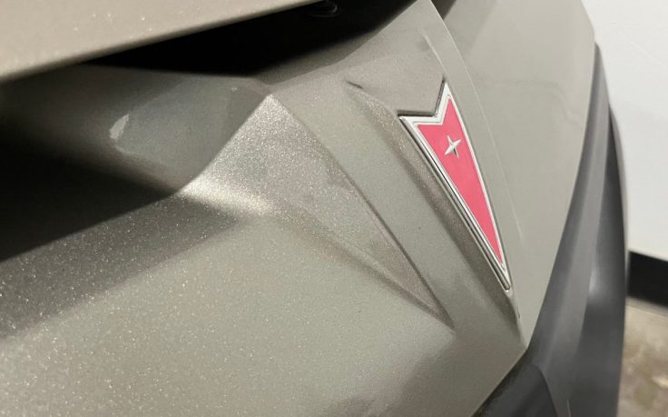 Close-up of the Pontiac logo on the front of a vehicle, showcasing the emblem against a textured surface.