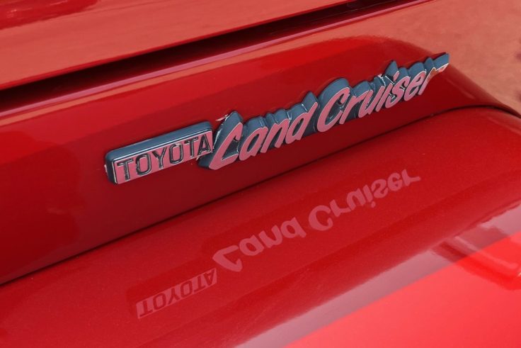 Close-up of a Toyota Land Cruiser badge on a red vehicle
