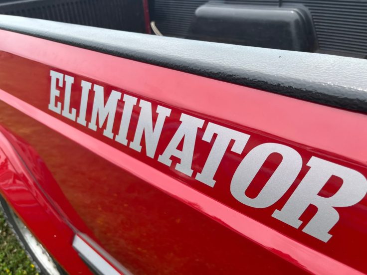 Close-up of the word 'ELIMINATOR' in silver lettering on the side of a special Jeep Comanche.