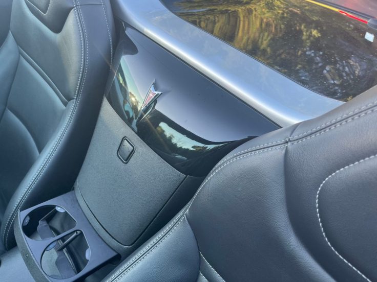 Interior view of Pontiac Solstice showing black leather seats and a glossy black panel with a reflection.