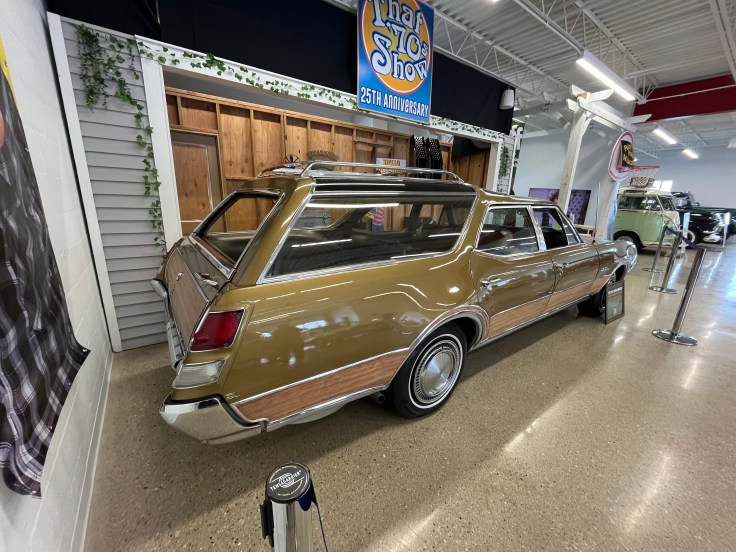 Old Vista-Cruiser station wagon displayed at Gallery setting with a 'That 70s Show' 25th anniversary sign in the background.