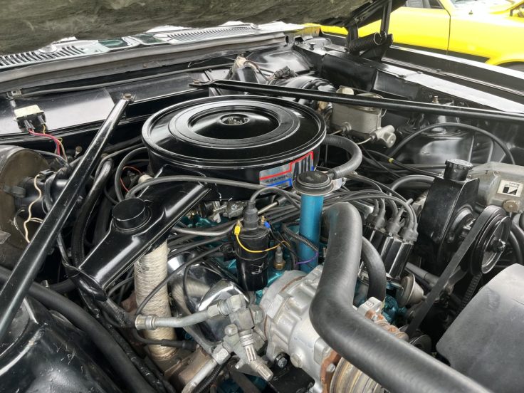 Close-up view of a vintage car AMC 401 V8 engine showcasing various mechanical components such as the air intake, fuel lines, and engine block.
