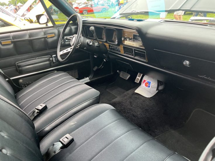 Interior view of a 74 AMC Ambassador showcasing black leather seats, steering wheel, and dashboard with retro details.