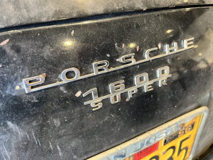 Close-up of the rear emblem of a black Porsche 1600 Super, showing the brand name and model designation.